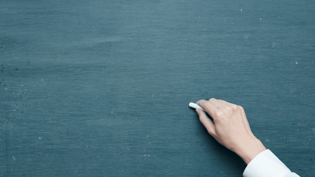 hand holding chalk up to chalk board