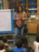 Saleema Noon in a classroom showing young kids a book with a pop-up picture of a growing baby